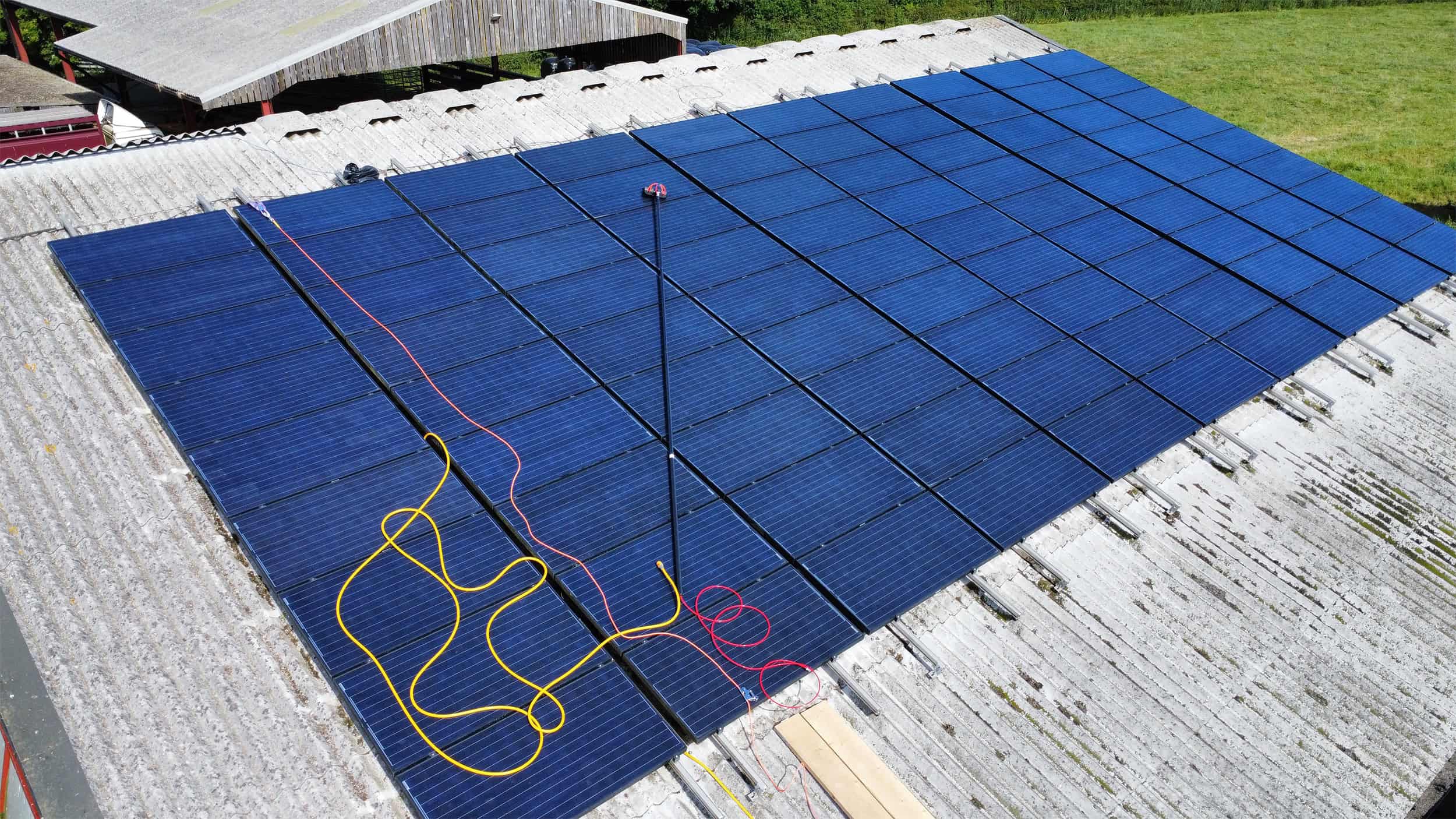 A large solar panel grid on the roof of a barn in the UK, being cleaned by EV Solar.